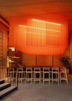 an empty room with many chairs and tables on the floor in front of orange curtains