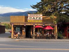 the outside of a restaurant with tables and umbrellas on the side of the street