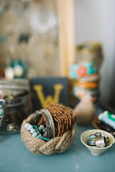 several bracelets and rings are on a table next to other beads, jewelry, and jars