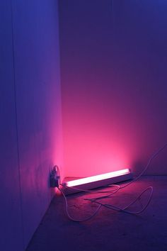 a purple light shines brightly in the corner of a room with no one around it