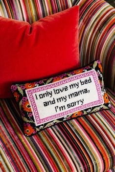 a pillow that is sitting on top of a striped couch next to a pillow with the words i only love my bed and my mama, i'm sorry