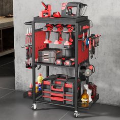 a red tool cart with tools and other items on it in front of a gray wall