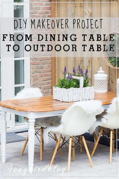 an outdoor table with white chairs and plants on it in front of a brick wall