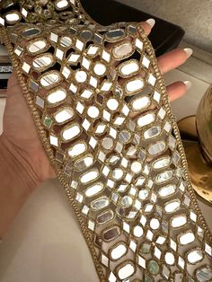 a woman's hand holding up a gold cell phone case that is covered in sequins