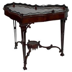 an ornately decorated wooden table with glass top and metal trimmings on the legs