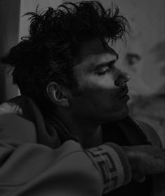 black and white photograph of a man leaning against a wall with his head tilted to the side