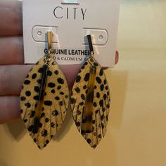 a pair of leopard print leather earrings with black and yellow details on the back of them