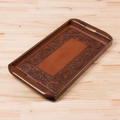 a brown leather tray on a wooden table