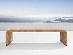 a wooden bench sitting on top of a white floor next to a wall and ocean