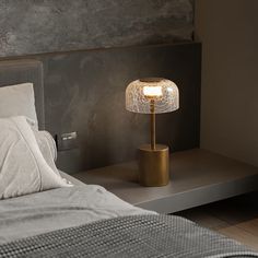 a lamp that is sitting on top of a table next to a bed with pillows