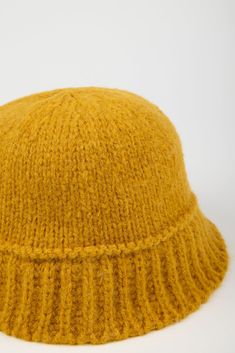 a yellow knitted hat is shown against a white background, with the top part visible