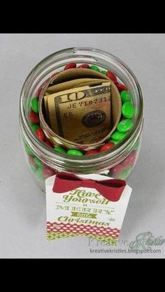 a jar filled with candy and money sitting on top of a table next to a card