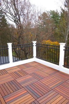 an outdoor deck with wooden flooring and black iron railings