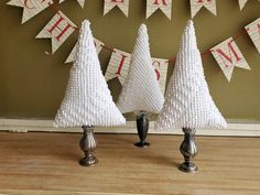 three christmas trees made out of plastic beads and burlocks are on display in front of a welcome sign