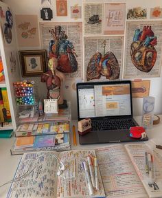 an open laptop computer sitting on top of a desk next to books and other items