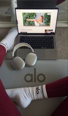 an open laptop computer sitting on top of a desk next to headphones and socks