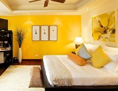 a bed room with a neatly made bed and yellow walls