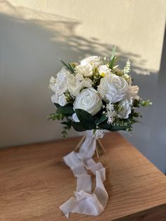 a bouquet of white flowers sitting on top of a wooden table