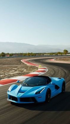 a blue sports car driving on a race track