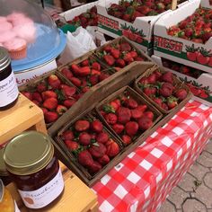 strawberries and jams are on display for sale at an outdoor farmers'market