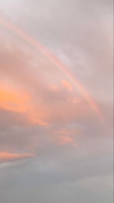 the sky is pink and cloudy with a rainbow in it