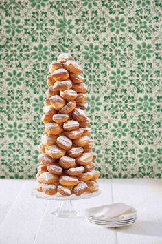 a stack of doughnuts sitting on top of a glass plate next to a green wall