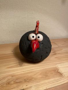 a rock with a face painted on it sitting on top of a wooden table next to a white wall