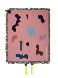 a pink rug with black, blue and green shapes on the front has yellow legs