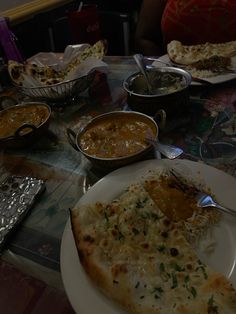 a table topped with lots of plates and bowls filled with different types of food covered in sauces