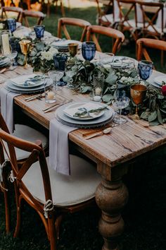 a table set with plates and place settings for an outdoor dinner party in the grass