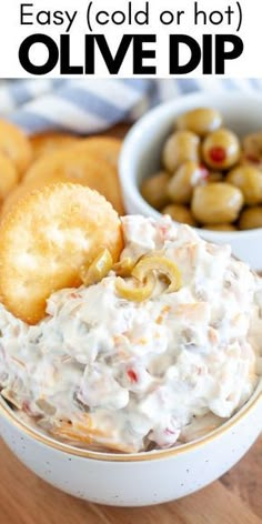 an image of a bowl of dip with olives and crackers on the side