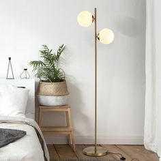 a bedroom with a bed, plant and two lamps on the floor next to it