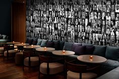 a restaurant with many tables and chairs in front of a wall covered with pictures on it