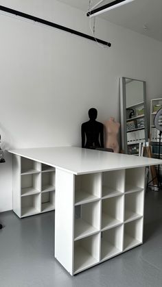 a white desk with shelves and a black mannequin sitting on top of it