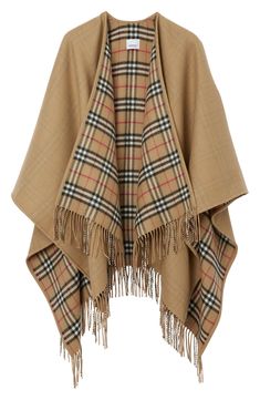 Warming merino wool in a luxurious double weave is fashioned into this perfectly fringed cape that can be worn with either the solid or check side out. 20 1/2" to 32 1/2" length; 3 1/2" fringe (One Size) Open front 100% merino wool Dry clean Made in the UK Women's Designer Clothing Burberry Poncho, Burberry Cape, Mantel Cape, Poncho Shawl, Brand Icon, Burberry Vintage, Wool Cape, Burberry Jacket, Cape Coat