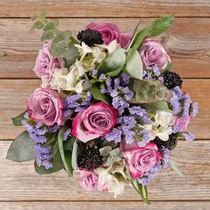 a bouquet of flowers sitting on top of a wooden table next to a wood wall