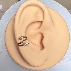 two gold rings sitting on top of a white plate next to an ear shaped cake