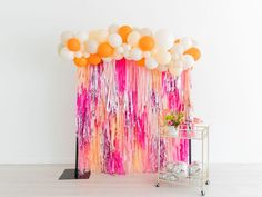 the balloon wall is decorated with pink, orange and white streamers