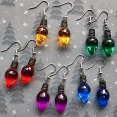 six different colored christmas lights hanging from silver earwires with snowflakes in the background