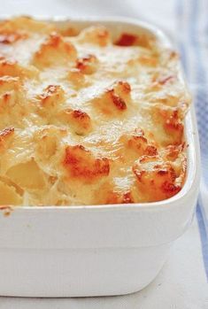 a casserole dish with cheese and sauce in it on a blue and white cloth