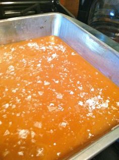 a metal pan filled with orange sauce on top of a stove next to an oven