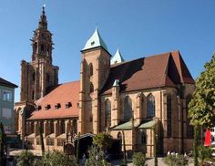 an old church with two towers on the top and green roof, surrounded by greenery