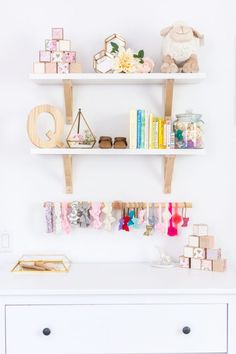 a white dresser topped with lots of shelves filled with books and other items on top of it