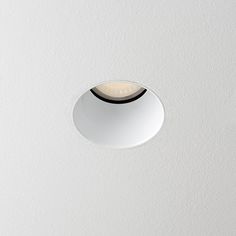 a round light fixture mounted on the ceiling in a white room with a black trim