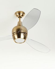 a gold ceiling fan with white blades and a clear glass blade on it's side