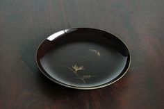 a black and gold plate sitting on top of a wooden table