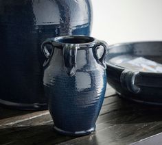 a blue vase sitting on top of a wooden table next to other plates and bowls