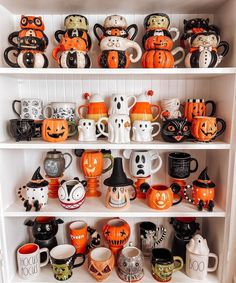 a white shelf filled with lots of halloween mugs