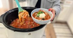 a woman is holding a bowl of food in her hand and stirring it into the slow cooker