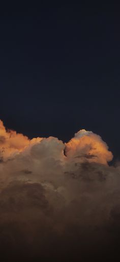 the plane is flying high in the sky at night time, with clouds behind it